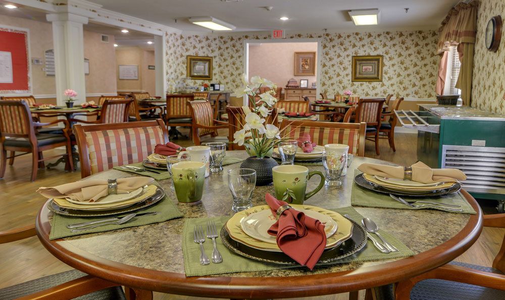 A warmly decorated dining room with elegantly set tables, featuring floral arrangements and neatly arranged tableware.