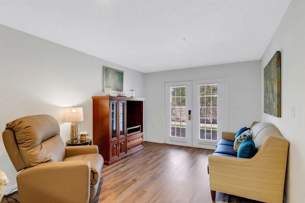 A cozy living room with comfortable seating and natural light streaming through French doors.