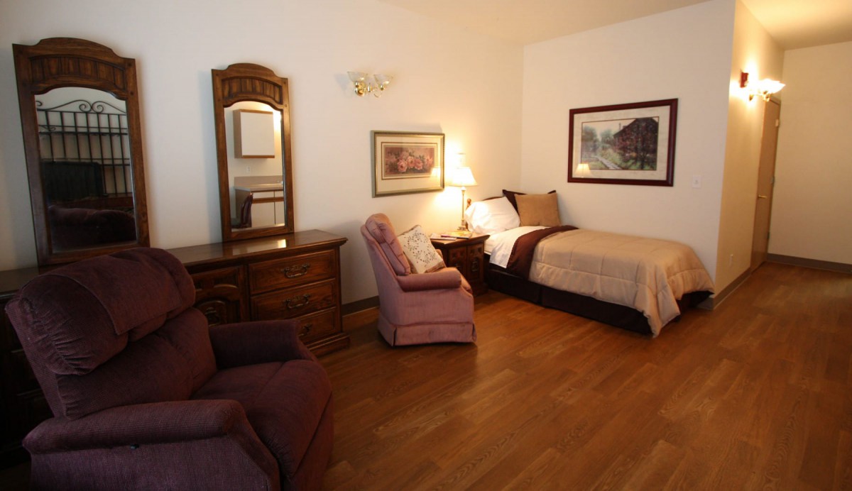 Cozy bedroom with a single bed, armchairs, and classic wooden furniture.