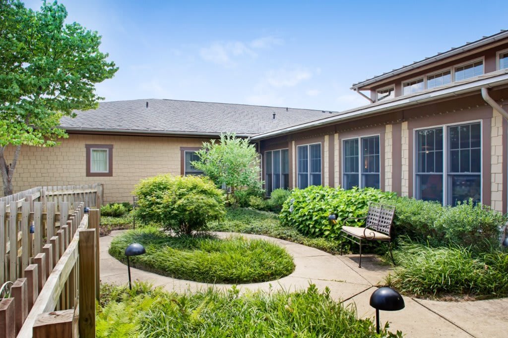 A tranquil courtyard with lush greenery and a wooden bench.
