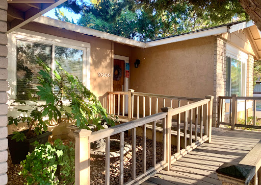 A welcoming entrance featuring a wooden ramp surrounded by greenery.