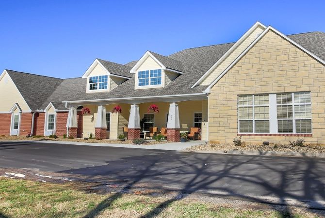 A large residential house with a front porch and multiple windows under a clear blue sky.