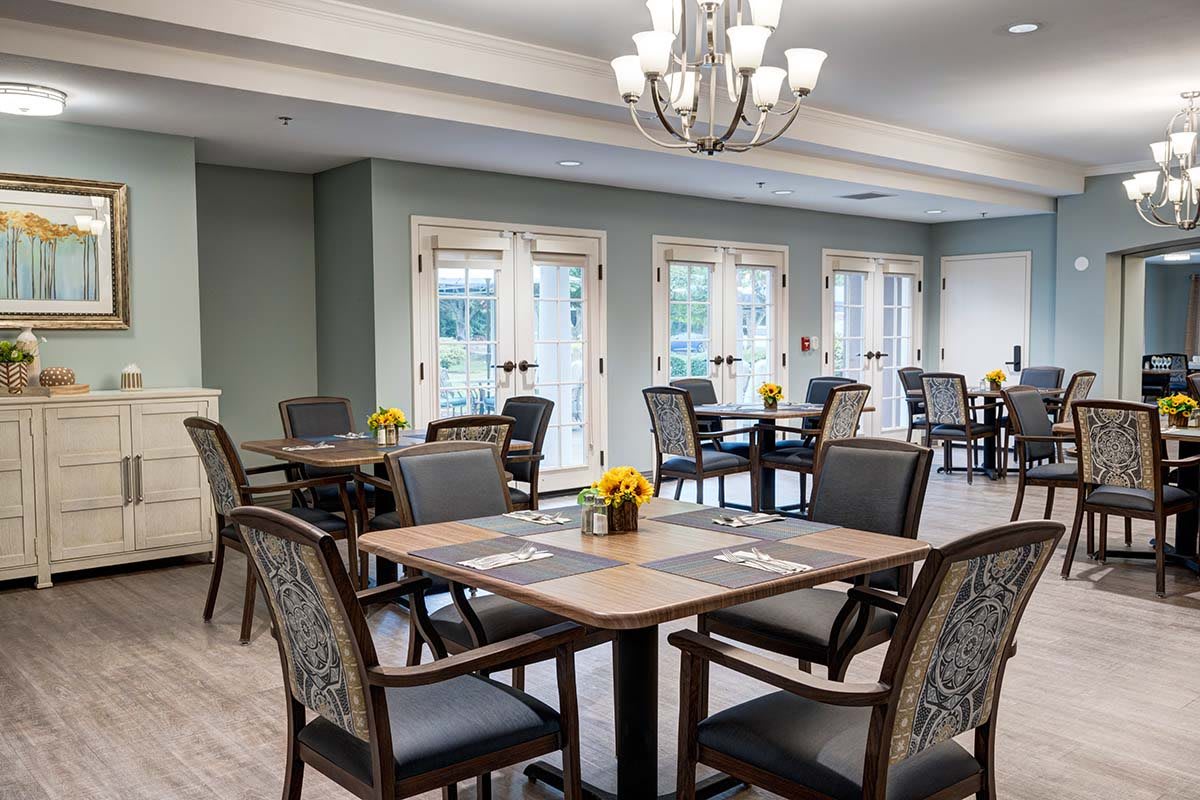 A well-decorated dining area with neatly arranged tables and chairs, illuminated by a stylish chandelier.