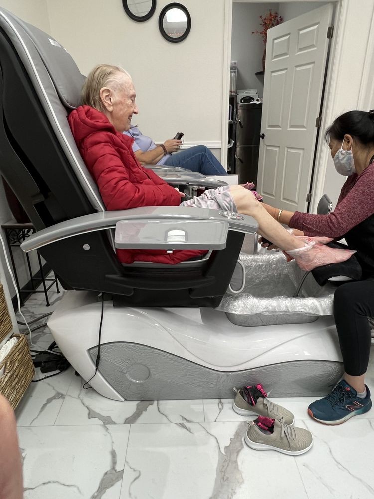 An elderly person enjoys a relaxing pedicure at a salon, seated in a massage chair.