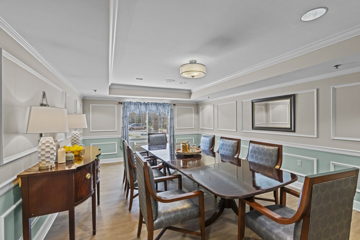 A well-decorated dining room with a large table and several chairs, featuring elegant interior design elements.