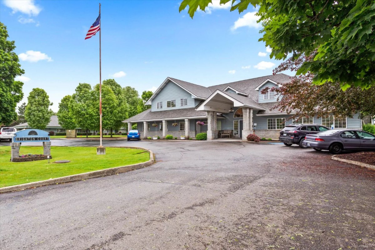 A building with a prominent entrance and an American flag in front, surrounded by trees and a parking area.