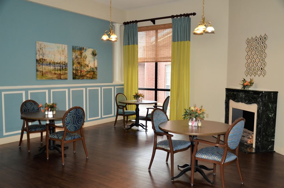 A cozy dining area with elegant tables, chairs, and decorative paintings on the wall.