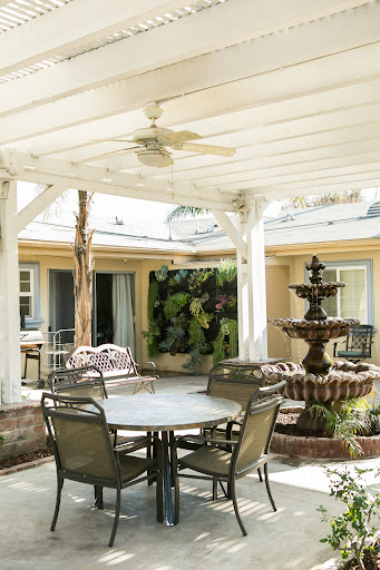 A serene outdoor patio with a fountain, seating area, and lush greenery.