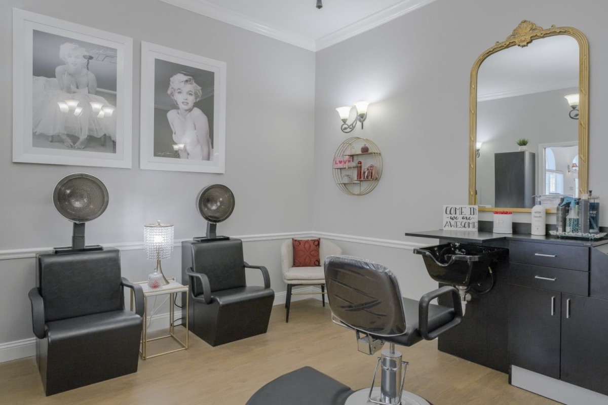 A stylish hair salon interior with chairs, mirrors, and decorative photos on the walls.