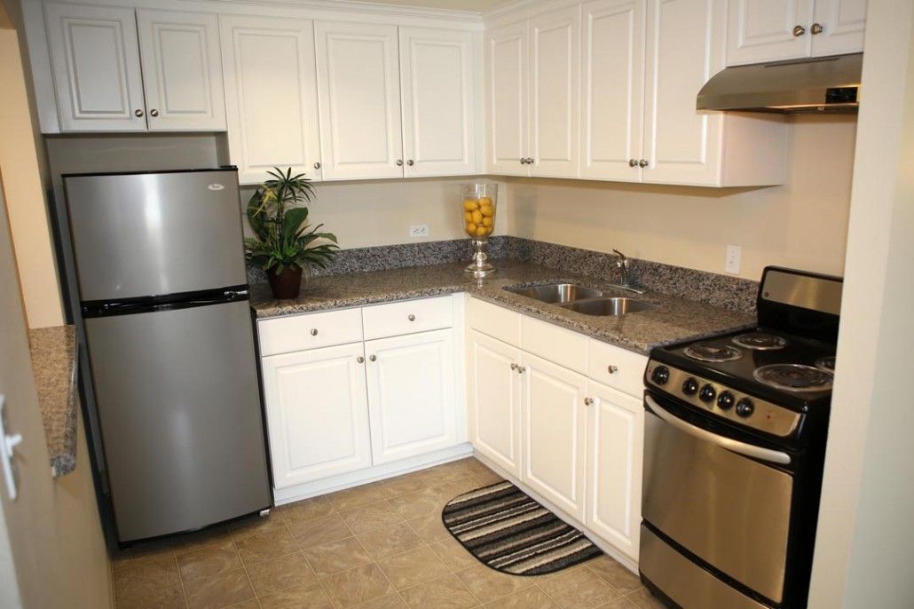 A modern kitchen with white cabinets, stainless steel appliances, and a granite countertop.