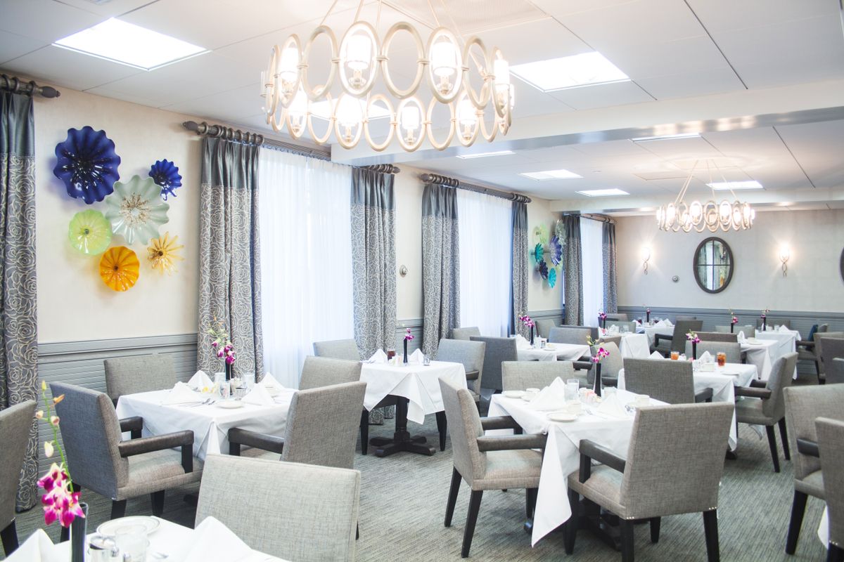 A beautifully decorated restaurant dining area with elegantly set tables and a chandelier.