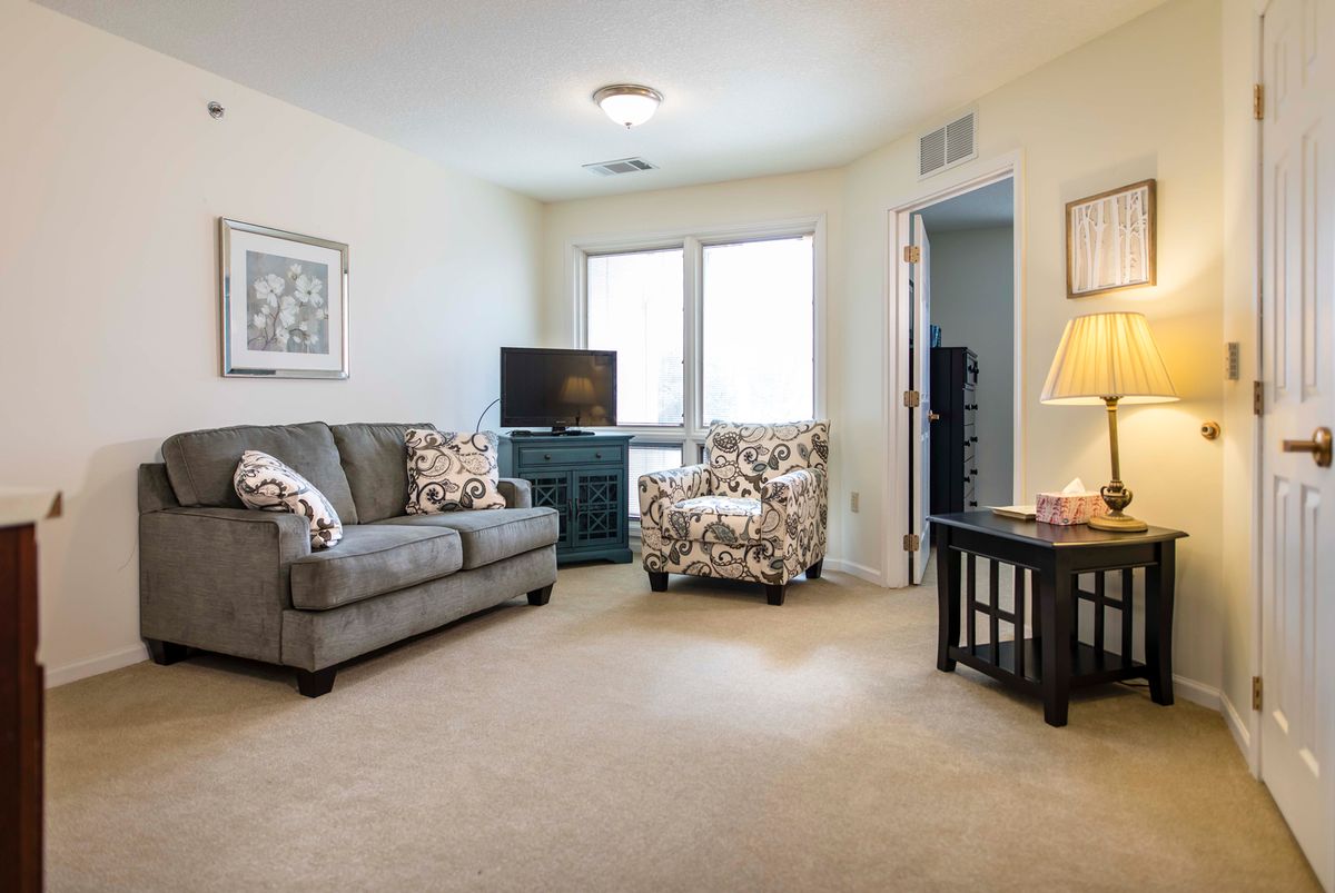 A cozy living room with a sofa, armchair, and TV.
