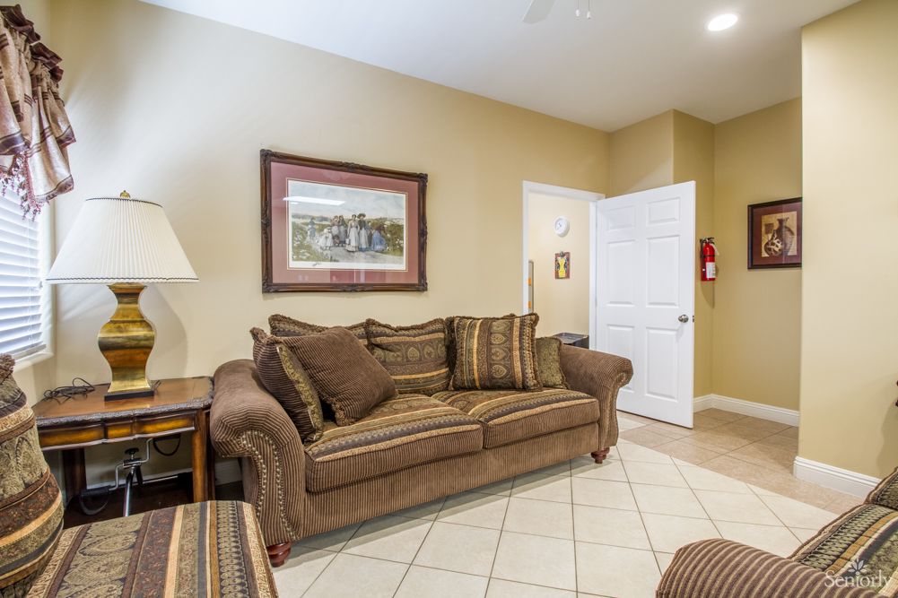 A cozy living room with a brown sofa, lamp, and wall art.