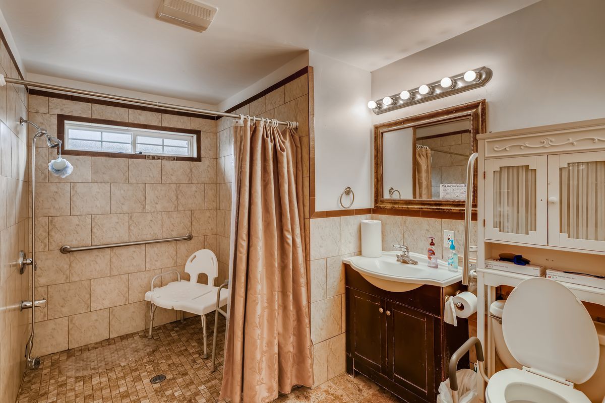 An accessible bathroom with a shower area, sink, vanity mirror, and a curtain.