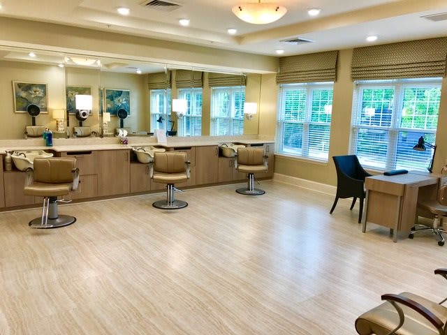 A modern and well-lit salon with multiple barber chairs and large mirrors.