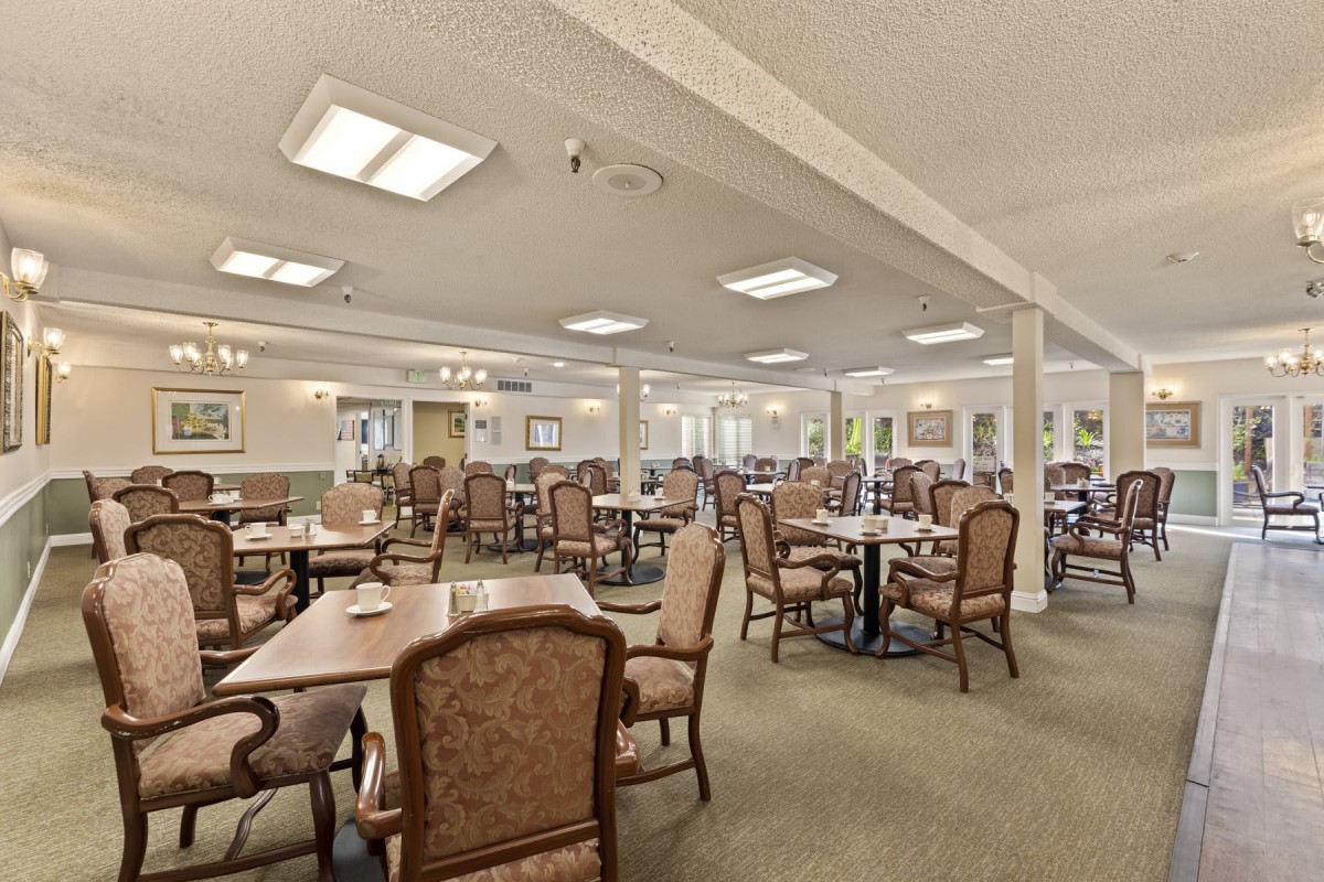 Spacious dining room with neatly arranged tables and chairs, well-lit and featuring elegant decor.