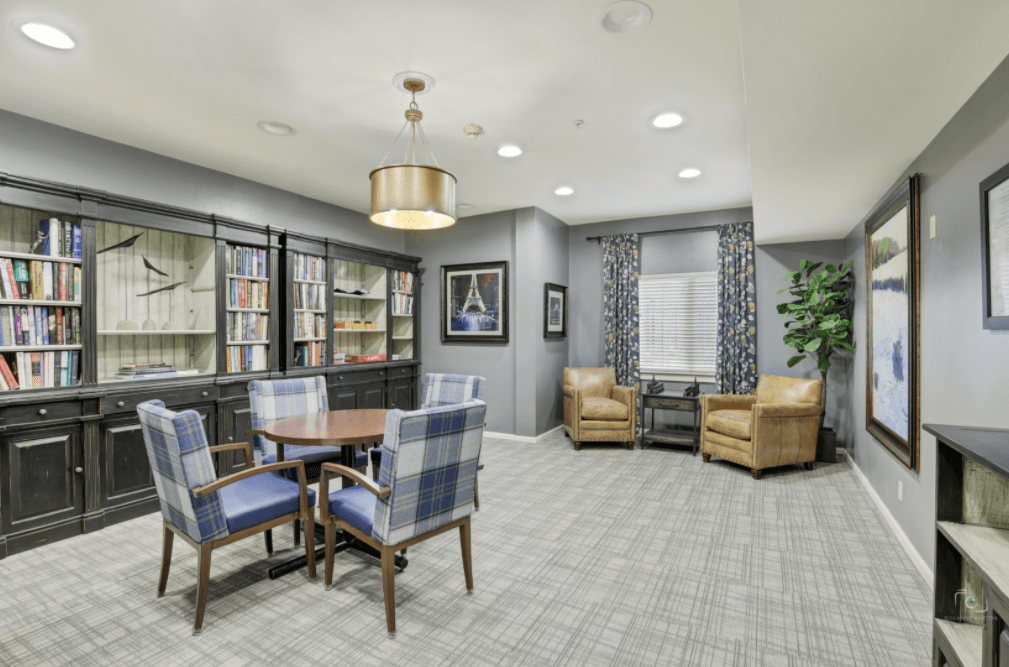 A cozy living room with a table and chairs, bookshelves, and comfortable seating.