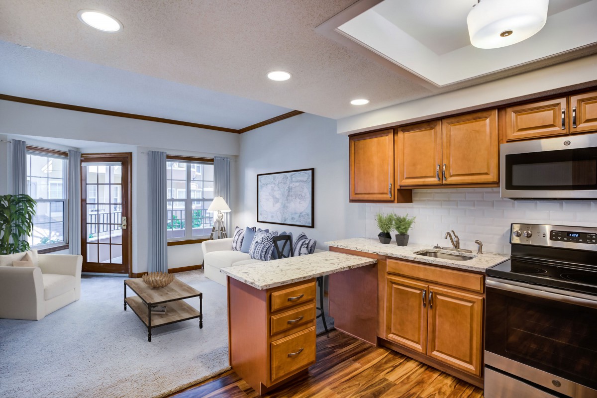 A well-lit open-concept kitchen and living room with wooden cabinets and modern decor.