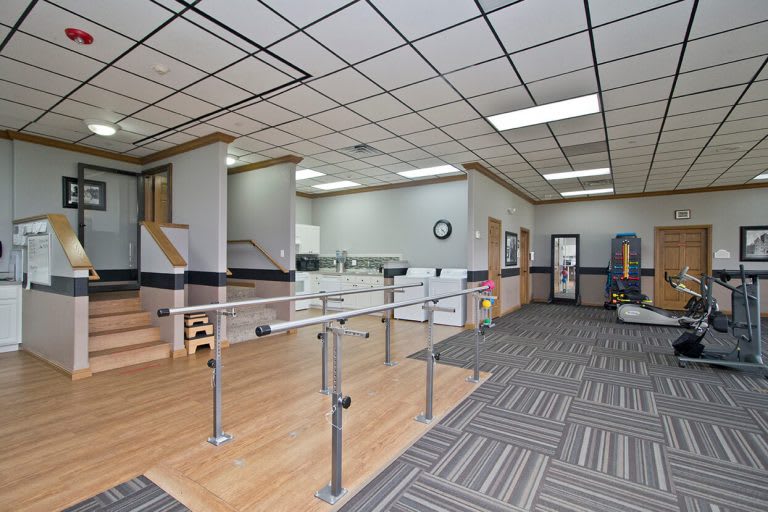 A rehabilitation clinic with exercise equipment and parallel bars for physical therapy.