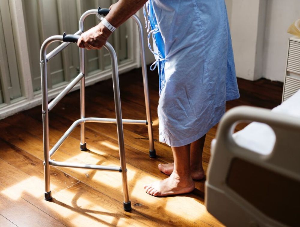 A patient using a walker in a hospital room for rehabilitation.