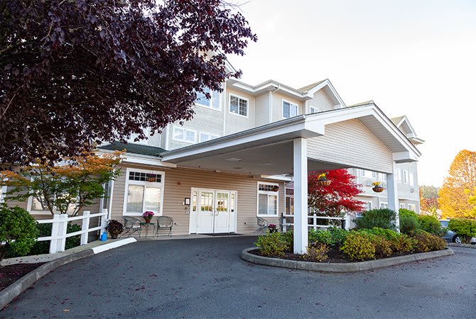 The front entrance of a building with landscaped surroundings and a covered porch.