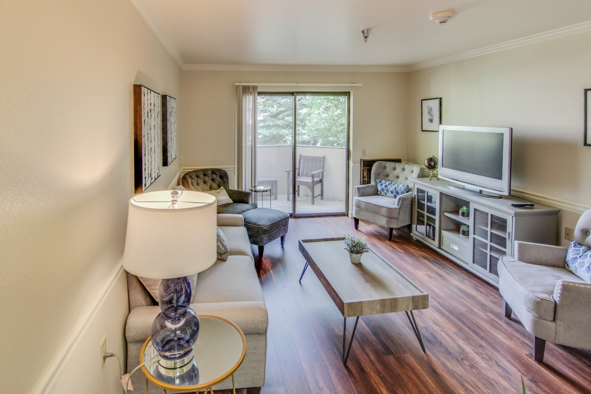 A cozy living room featuring modern furniture, wood flooring, and a sliding glass door that allows natural light to fill the space.