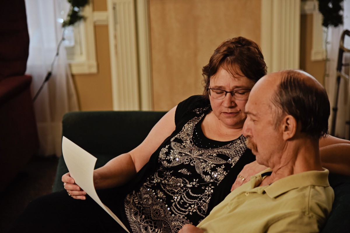 Two people sitting on a couch reviewing a document together.