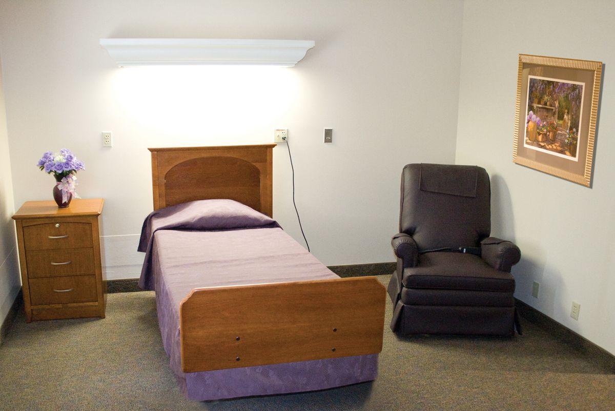 A minimalist bedroom with a single bed and a reclining chair.