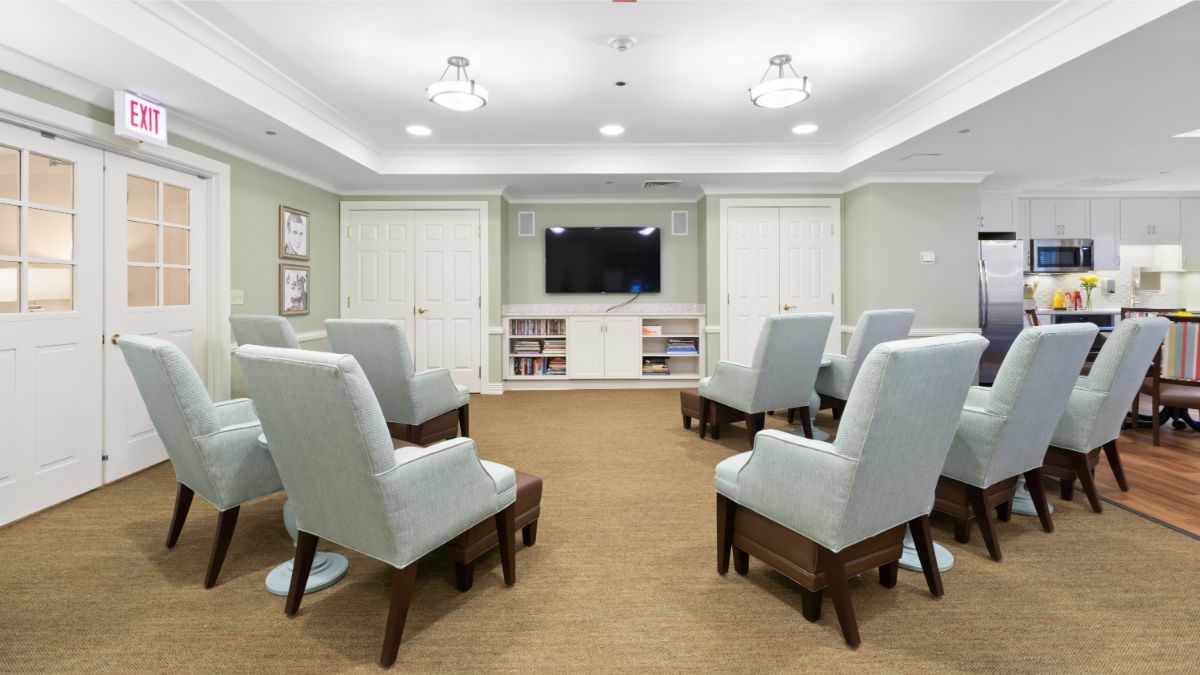A cozy meeting room with comfortable chairs arranged around a television.