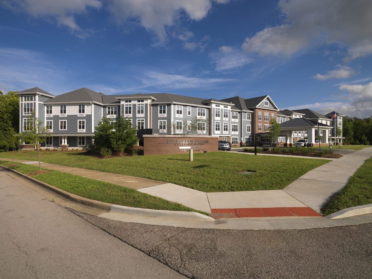 A modern apartment building with a well-kept lawn under a partly cloudy sky.