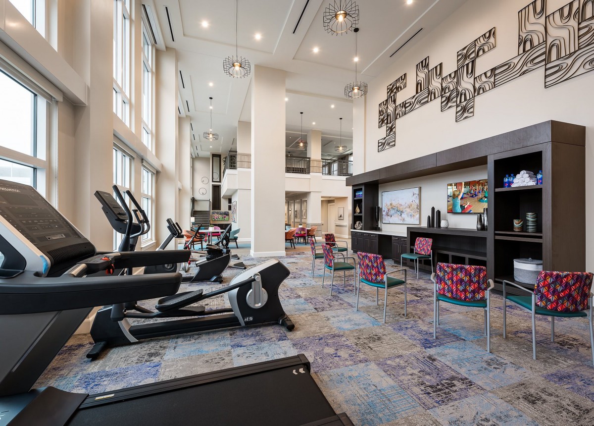 A modern gym with various exercise machines and ample natural light.