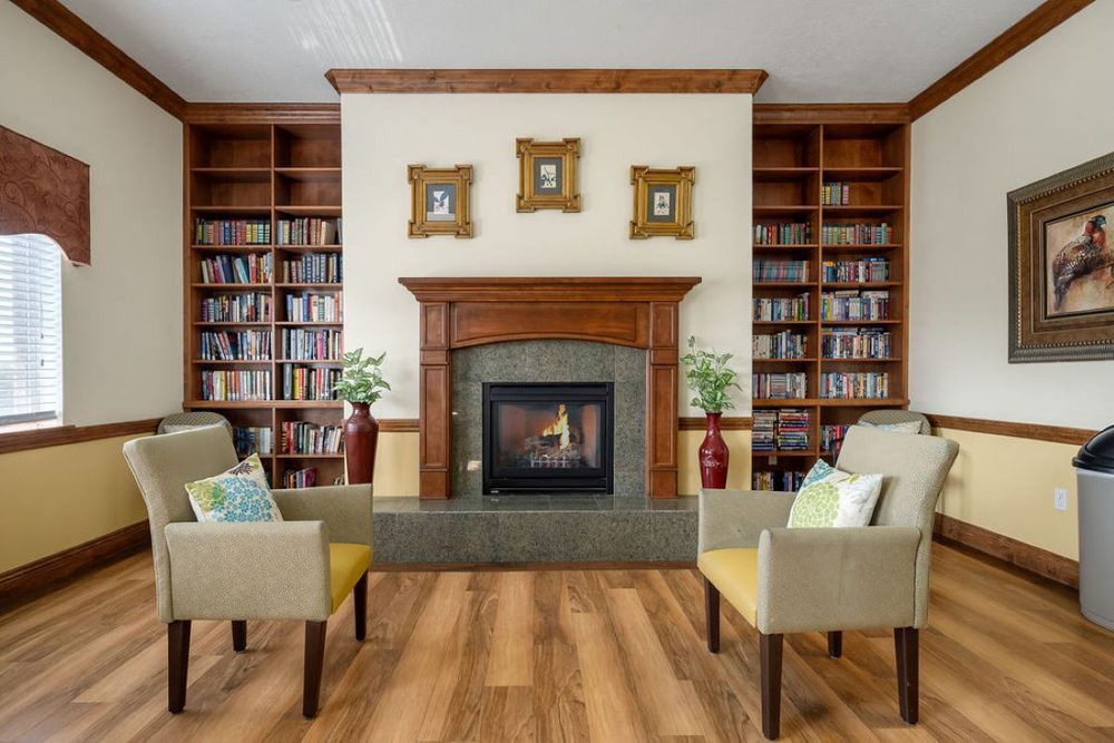 A cozy library room with a fireplace surrounded by bookshelves and comfortable seating.