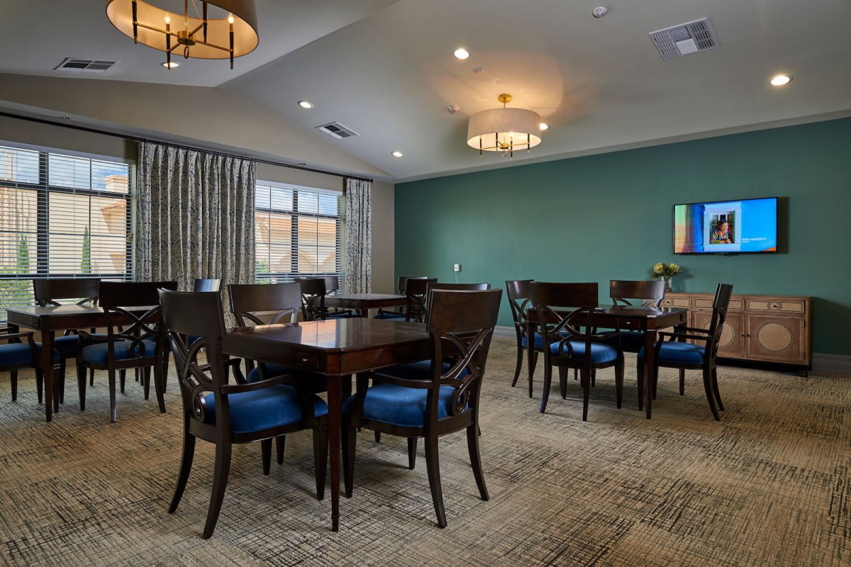 A well-lit dining room with multiple tables and chairs, featuring elegant lighting fixtures and modern decor.