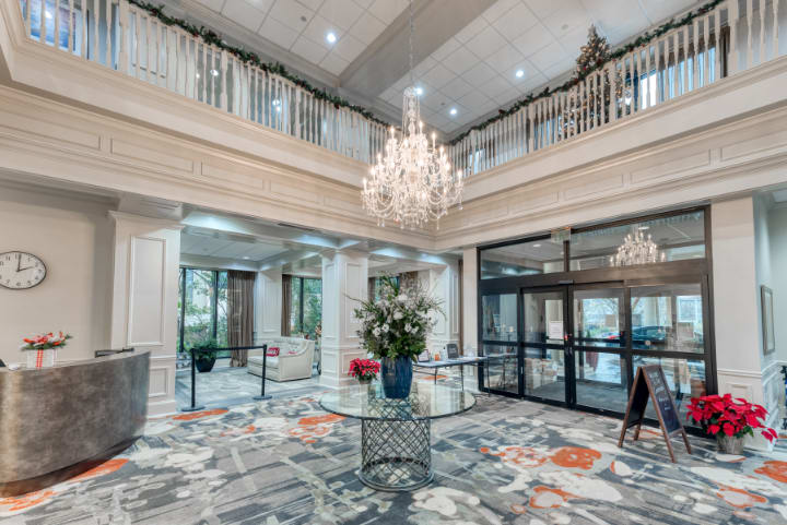 A spacious and elegantly designed lobby featuring a grand chandelier and floral centerpiece.