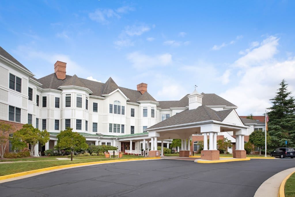 A large residential building with a landscaped entrance and clear blue sky.