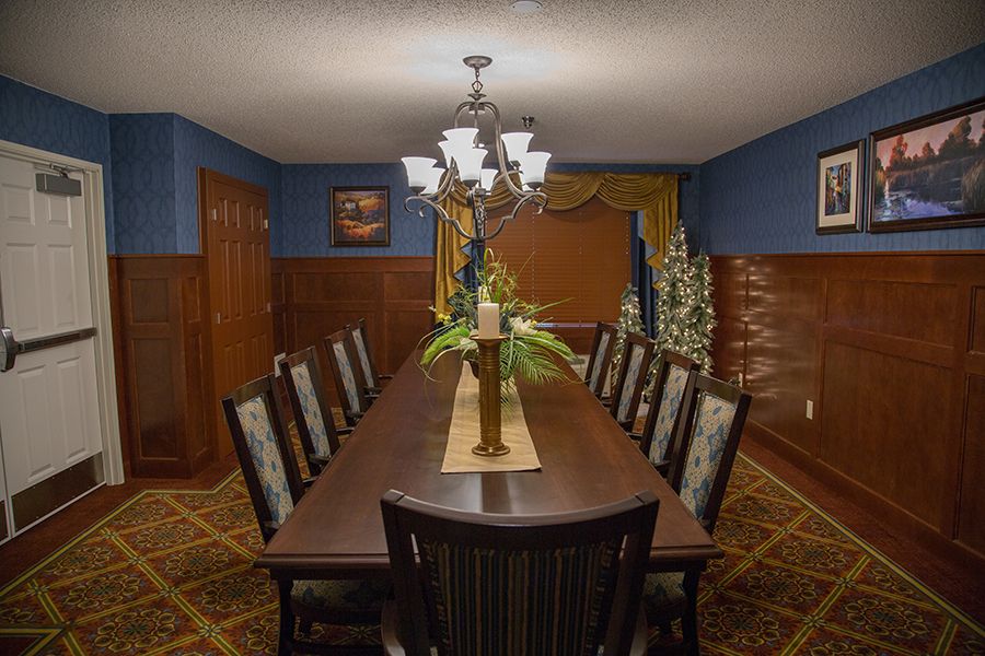 A well-decorated dining room with a long table, multiple chairs, and a chandelier overhead.