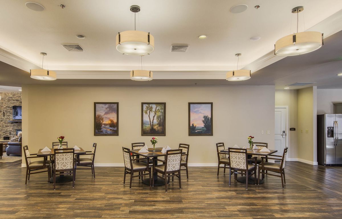 A modern dining room with neatly arranged tables and chairs, decorated with artwork on the walls.