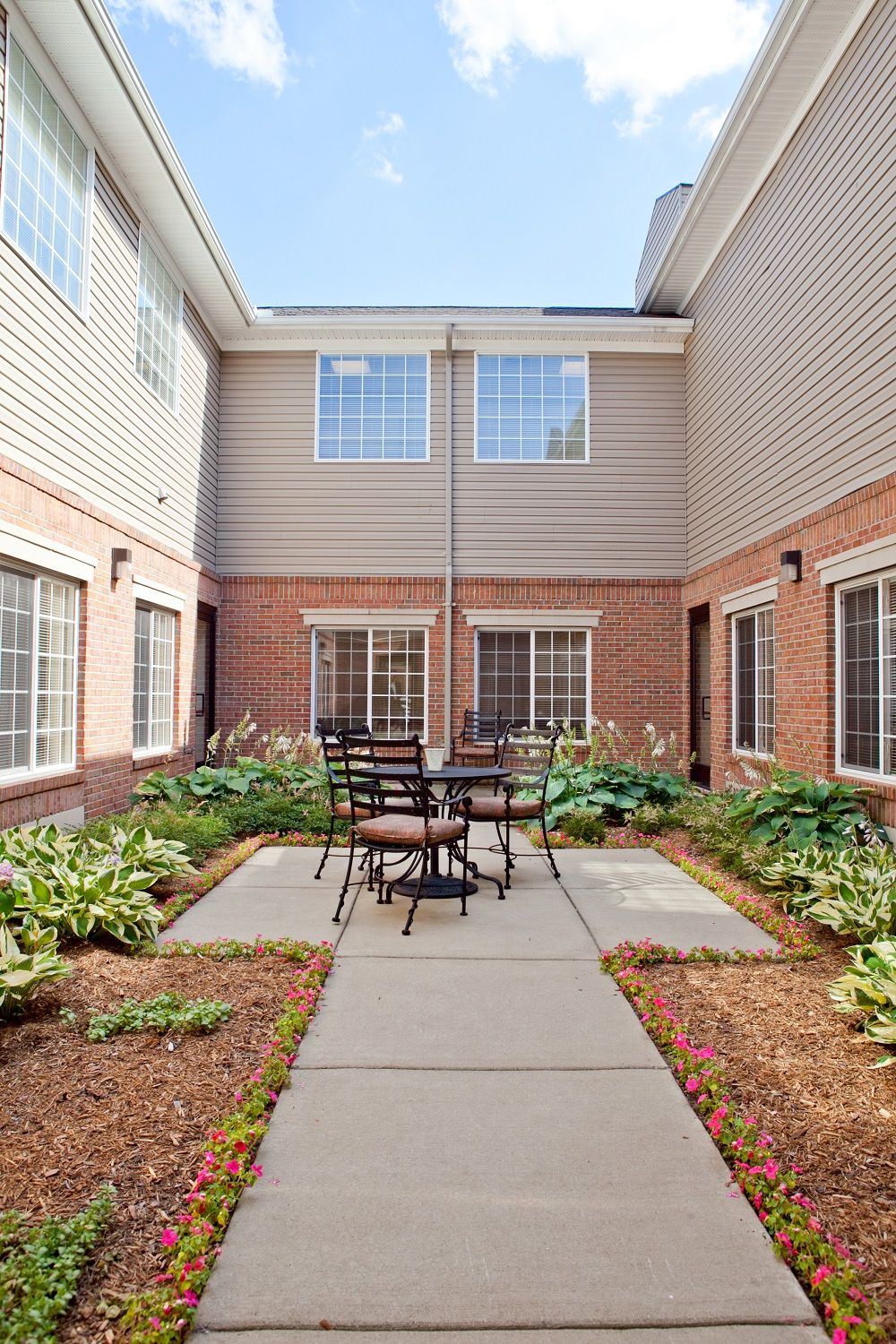 A cozy courtyard with a central table and chairs surrounded by greenery.
