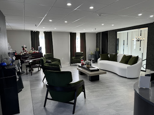 A modern and minimalist living room featuring green chairs and a white sofa, filled with natural light.