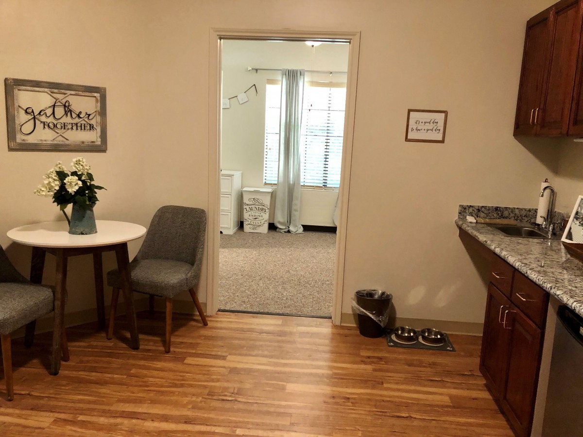 A cozy office space with a seating area, decorated with plants and artwork.