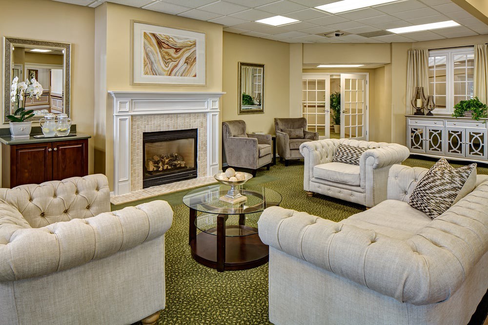 A cozy living room with elegant sofas, a fireplace, and a glass coffee table.