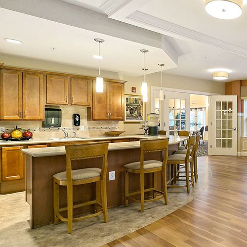 A modern kitchen with wooden cabinets and an open layout featuring a breakfast bar with barstools.