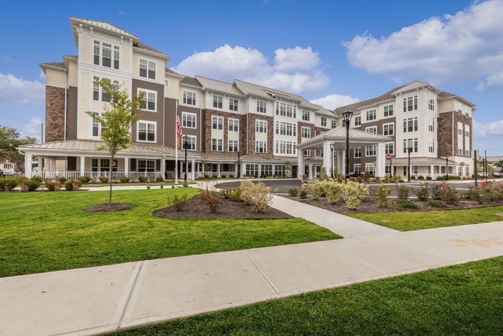 A modern residential building with landscaped grounds and a clear blue sky.