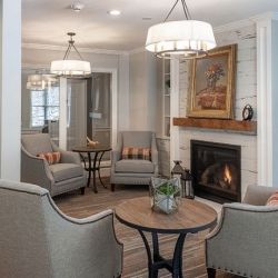 A cozy living room with armchairs, a fireplace, and elegant chandelier lighting.