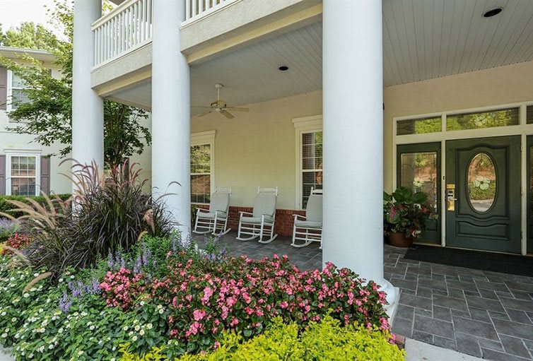 A charming porch with rocking chairs, surrounded by a vibrant garden of flowers.
