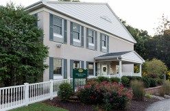 A two-story building with a landscaped front yard and a small porch.