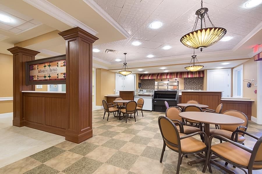 A well-lit dining area with tables and chairs adjacent to a kitchen space.