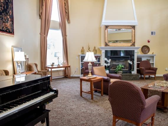 A cozy living room featuring a grand piano, comfortable seating around a fireplace, and tasteful decor.