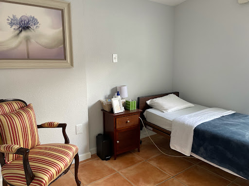 A simple and cozy room featuring a bed, a comfortable chair, and a decorative painting on the wall.