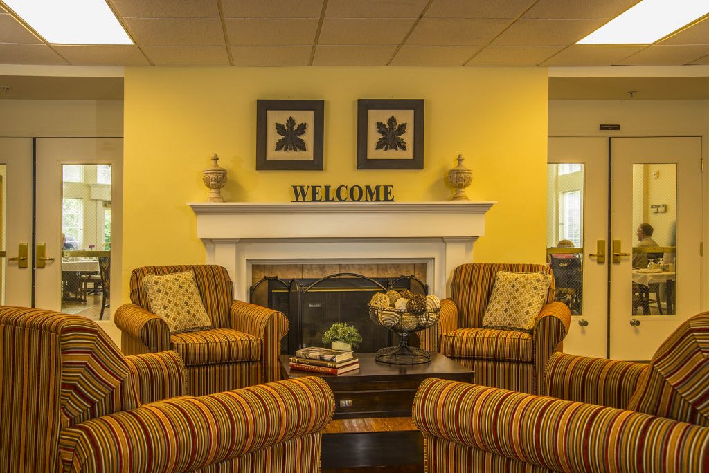 A cozy living room with a warm color scheme featuring striped furniture and a welcoming fireplace.
